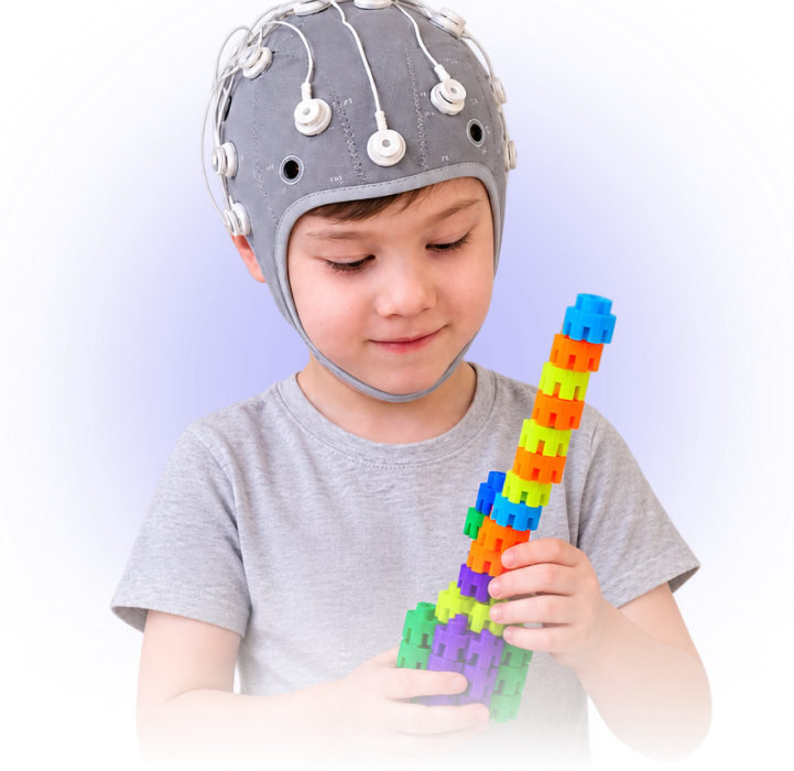 Niño con equipo de neuromodulación cerebral sosteniendo bloques de construcción en una imagen sobre valoración de candidatos pediátricos.